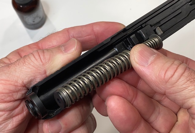 Place the recoil spring assembly into the slide with the larger plastic end facing the front