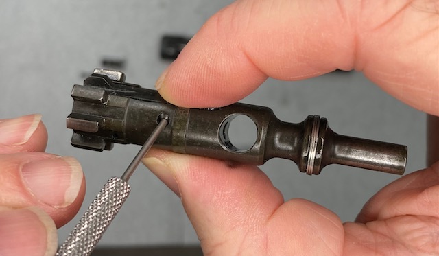 AR-15 BCG Disassembly: Squeeze the Extractor as shown and push the pin out with a small punch.