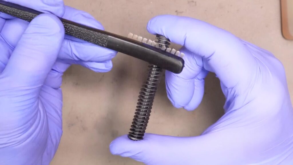 Use a dry brush to clean the recoil spring and guide rod