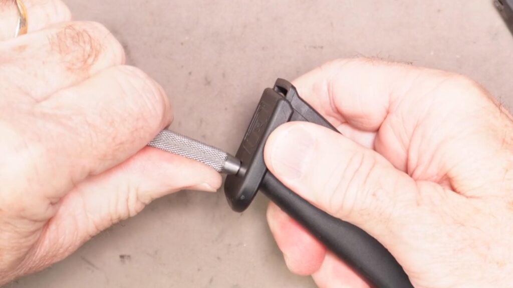 Using a pin punch to force the Glock magazine base plate off of the magazine tube