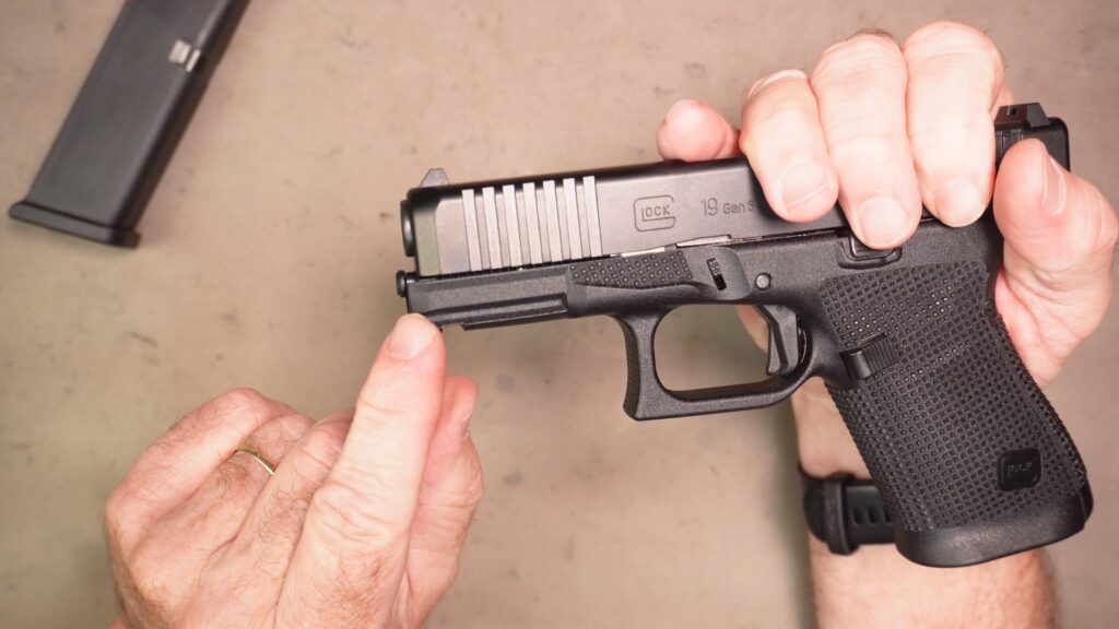With the trigger to the rear, press the slide back slightly as shown